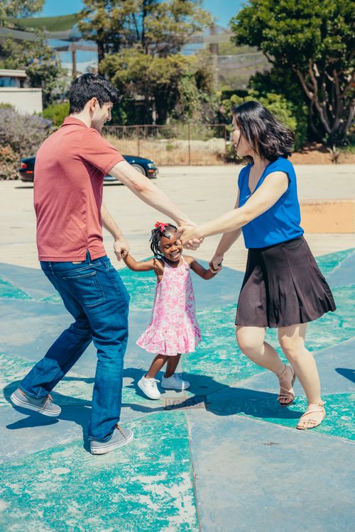 A child and two adults playing together outdoors.