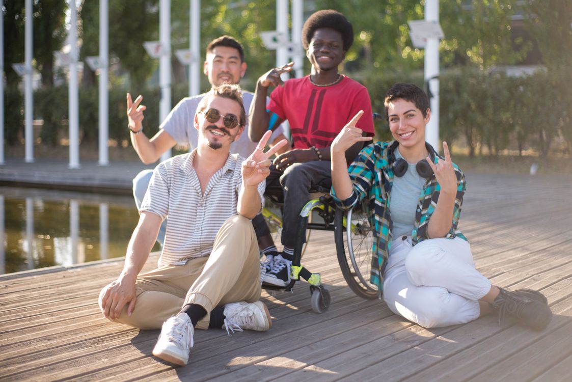 Friends spending time together outdoors, including a wheelchair user.